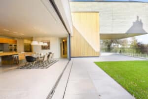 Modern open-plan home with a spacious dining area and large sliding glass doors opening to a patio with lush green lawn.