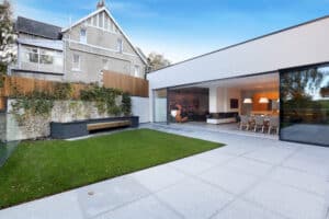 Modern house with large windows, spacious garden, and patio.
