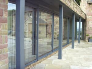 Large glass sliding doors with a stone wall exterior open onto a paved patio.