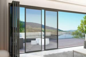Slide and turn doors open to a wooden deck with outdoor seating, offering breathtaking views of a scenic landscape featuring rolling hills and a tranquil body of water.