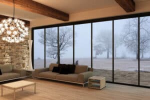 Modern living room with expansive sliding doors framing misty countryside views, showcasing IDSystems' slim-profile aluminium glazing design.