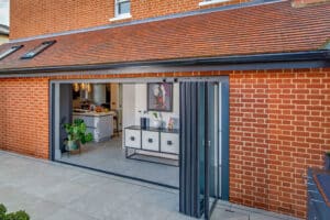 House with a large, open slide and turn doors seamlessly connecting the brick exterior to a modern kitchen interior.