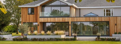 Large glazed sliding doors on timber clad home in Norfolk
