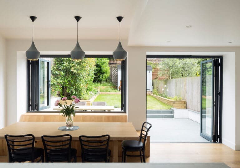 This stylish kitchen and outdoor seating area are joined by a bifold window and door