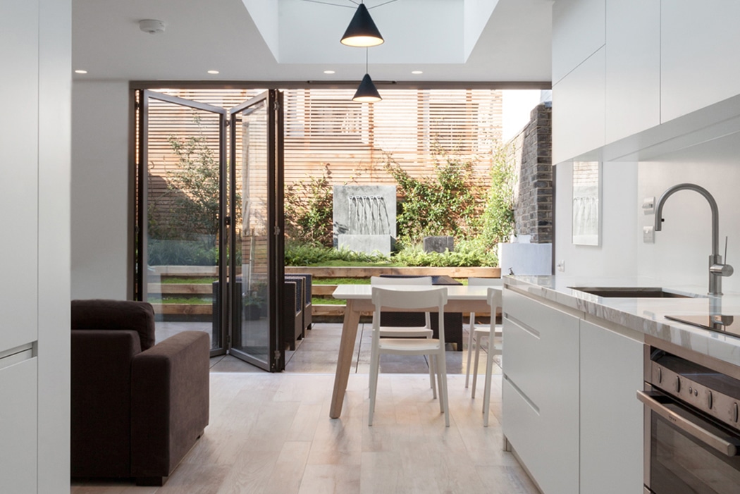 Are bifold doors a good idea? 3-panel bifold doors connect white kitchen with garden