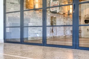 Double glazed bifold doors open to an industrial-style room with brick walls, large wall art, and vintage decor.