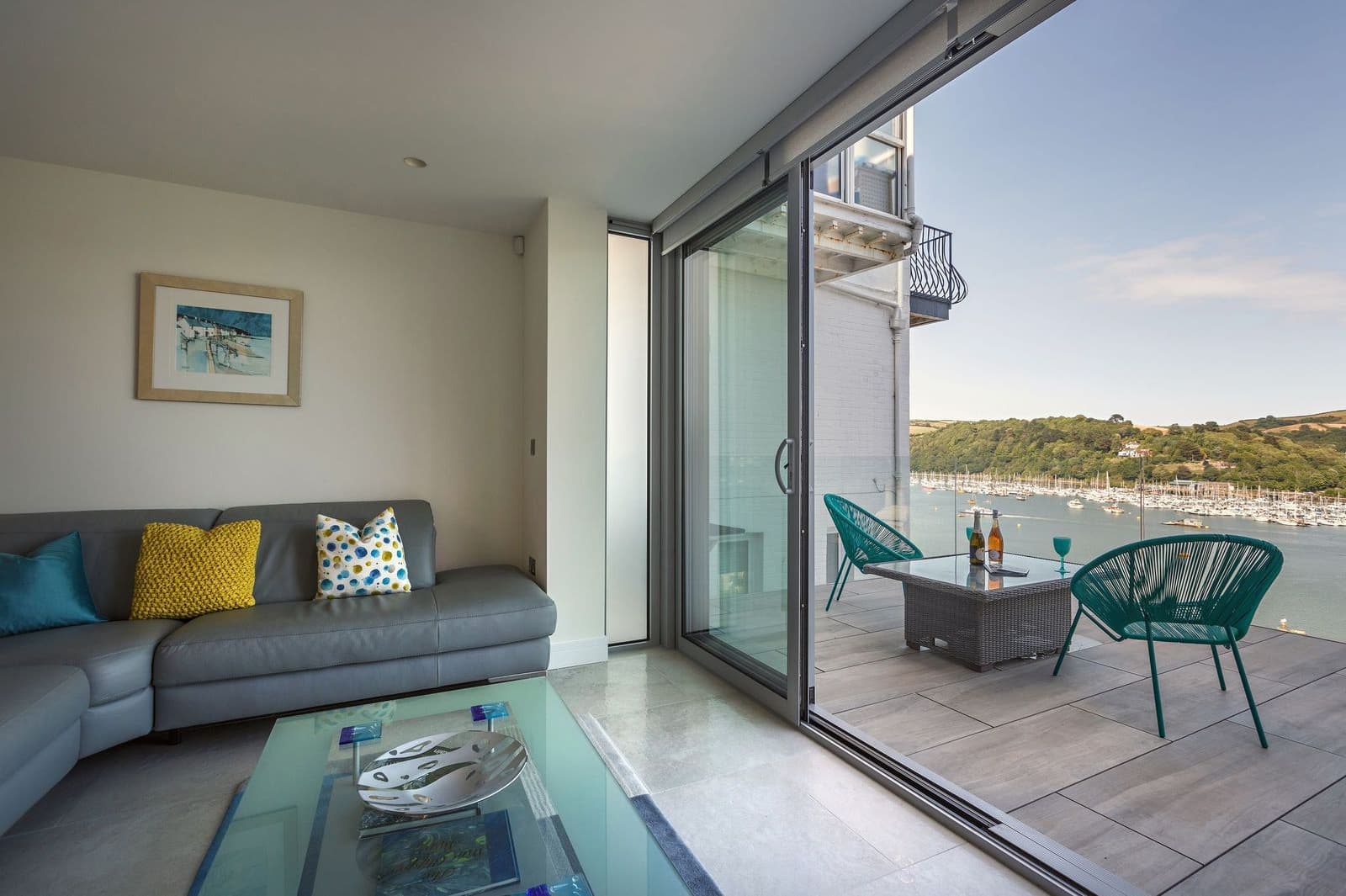A riverside house features sliding door that separate the internal living space and an outdoor balcony dining area, without blocking natural light.