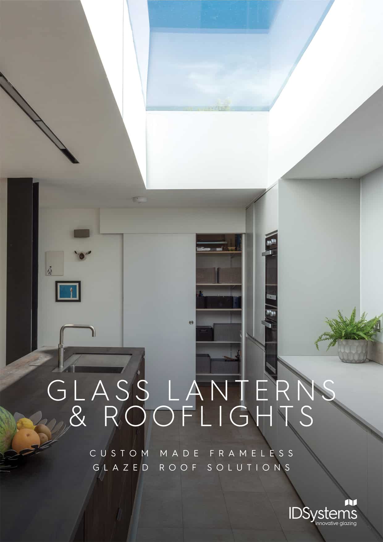 Modern kitchen featuring a large glazed rooflight, white walls, dark countertops, and built-in appliances. Text reads
