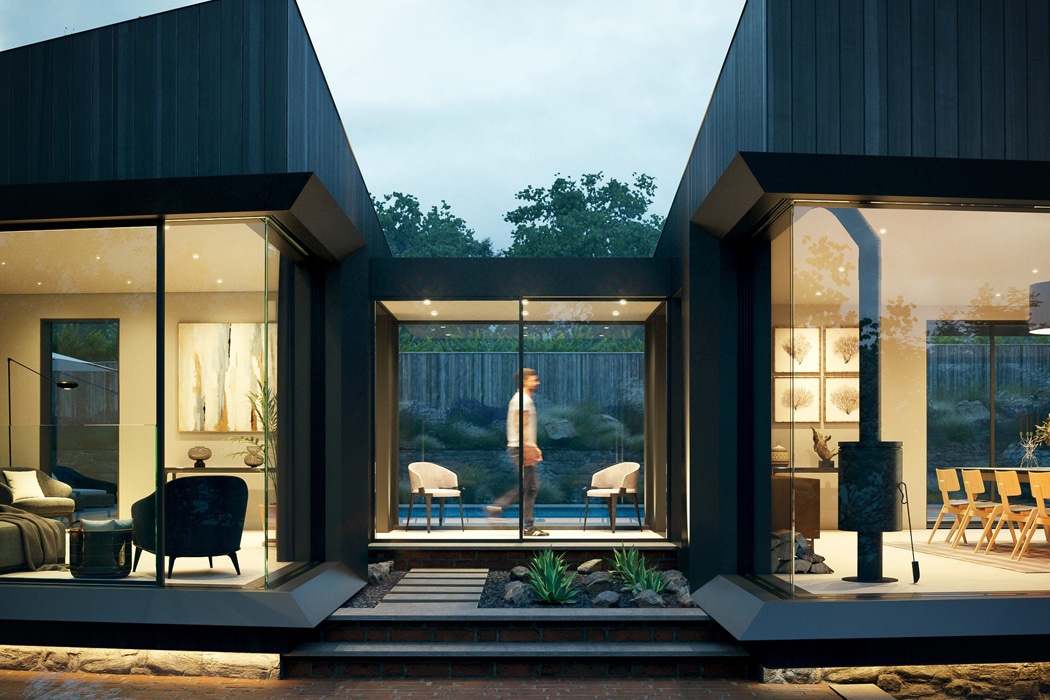 Modern home exterior at dusk with large glass windows showing indoor living and dining areas; a person walks through the central corridor between the two sections.