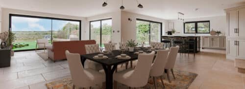 Spacious open-plan kitchen, dining, and living area with modern furniture, large windows, and views of a green landscape outside.