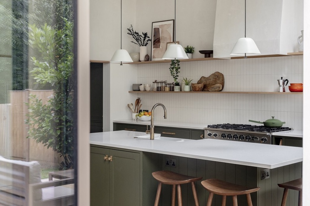 Contemporary kitchen with double-height glazing flooding space with natural light, featuring white cabinetry, open shelving, and garden views.