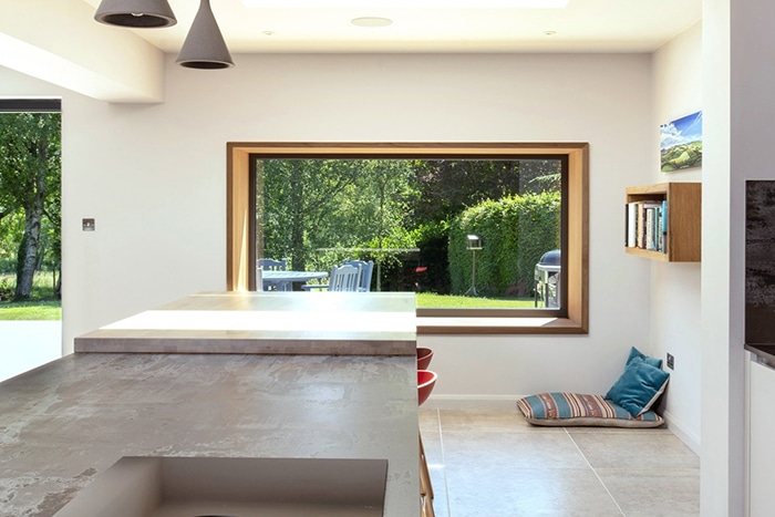 Modern kitchen extension with double-height glazing framing garden views, featuring slim-frame sliding doors and natural light flooding contemporary space.
