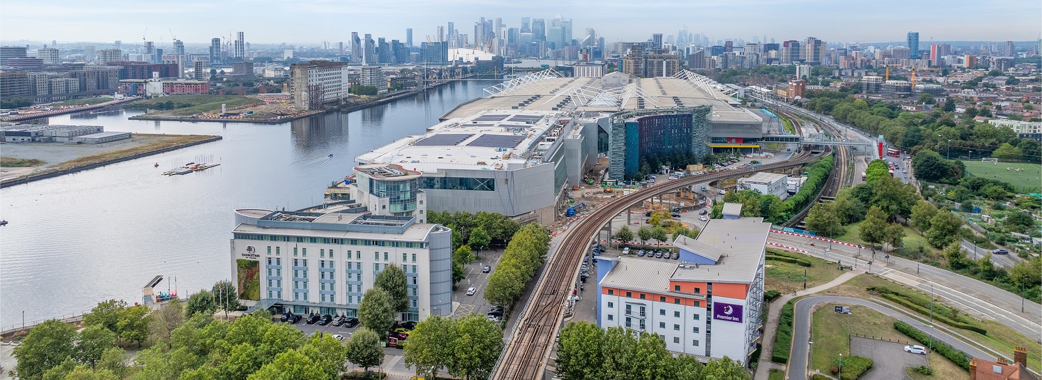 Aerial view of ExCel London venue with waterfront location, modern architecture, and city skyline backdrop.