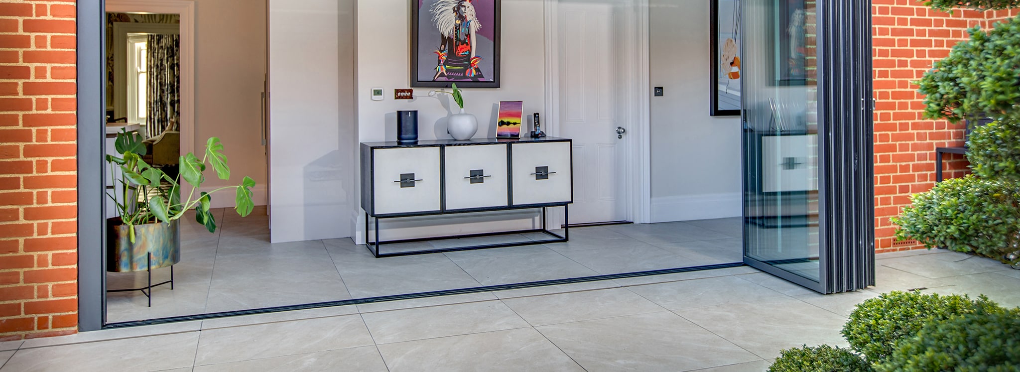 Modern entrance with Vistaline slide and turn doors opening onto patio, showcasing accessible glazing design and seamless indoor-outdoor flow.